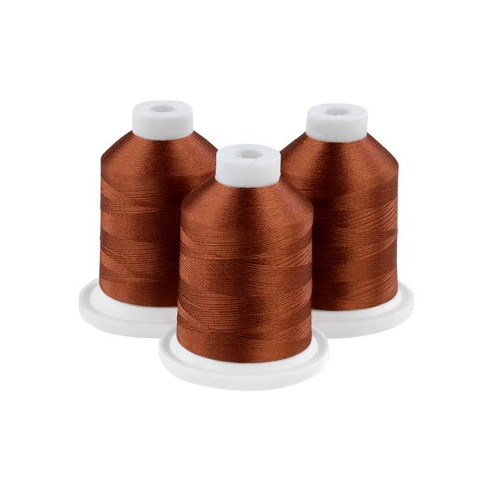 Three rust-colored embroidery thread spools with white caps on circular bases