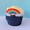 Cupcake with vanilla frosting and rainbow decoration in black wrapper