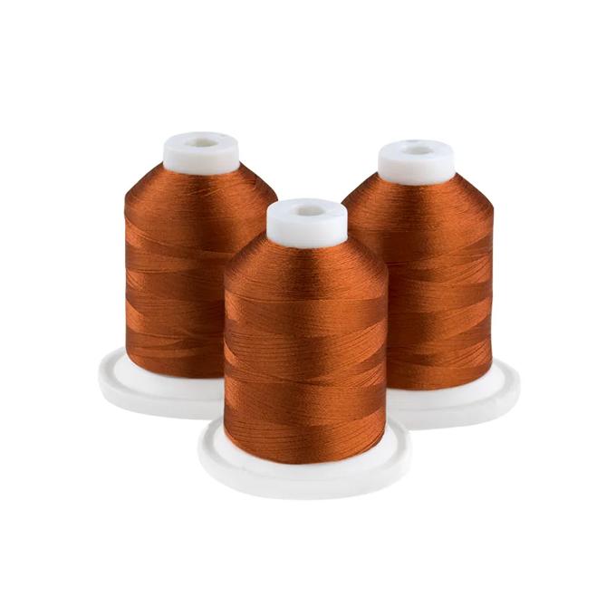 Three spools of rust-colored embroidery thread on white bases