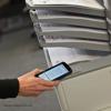 Hand using smartphone for wireless printing with Brother laser printer output tray