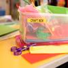 Labeled craft storage box with colorful supplies, scissors, and paper on workspace