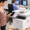 Woman using smartphone to control Brother MFC-L6915DW wireless all-in-one laser printer in office