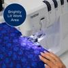 Brother sewing machine with LED-lit work area stitching blue fabric