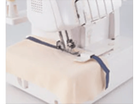 Brother serger sewing machine stitching fabric with navy blue thread on white surface