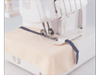 Brother serger sewing machine stitching fabric with navy blue thread on white surface