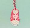 Pink and white checkered shoe ornament with striped ribbon on light blue background