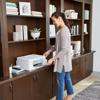 Woman using Brother all-in-one wireless printer in home office with bookshelf