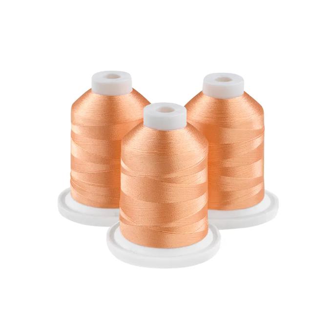 Three spools of mellow melon embroidery thread on white bases