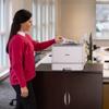 Woman retrieving document from Brother HL-L8570CDW color laser printer in office
