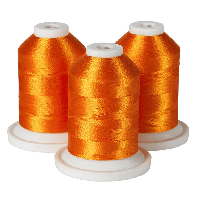 Three spools of Brother orange embroidery thread on white bases