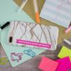 Smartphone with marble case, colorful markers, sticky notes, and paper clips on desk