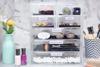 Clear acrylic makeup organizer with labeled drawers storing cosmetics and beauty tools