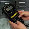 Brother label maker with QWERTY keyboard held in hands for portable labeling