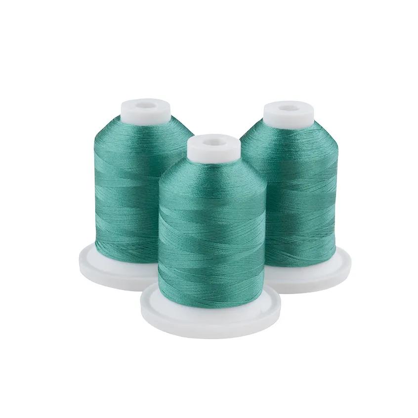 Three spools of blue-green embroidery thread on white bases