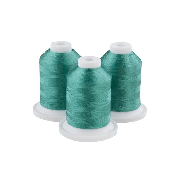 Three spools of blue-green embroidery thread on white bases