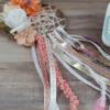 Handmade dream catcher with ribbons, flowers, and decorative embellishments on wooden surface