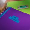 Brother label on purple notebook with green notebook in background on desk