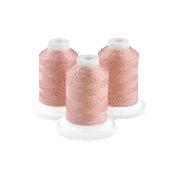 Three spools of flesh pink embroidery thread on white bases