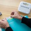 Brother P-touch label maker with hands inserting labeled dividers into turquoise file organizer