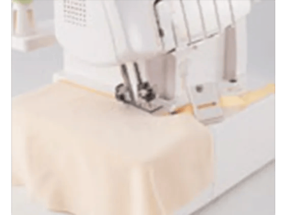 Brother sewing machine stitching cream fabric with yellow thread on white surface