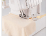 Brother sewing machine stitching cream fabric with yellow thread on white surface