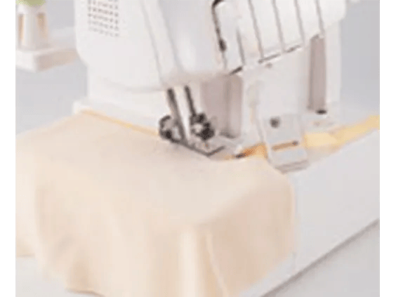 Brother sewing machine stitching cream fabric with yellow thread on white surface