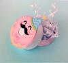 Two round bath bombs with pink and purple swirls and decorative ribbons on light blue background