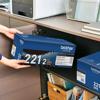 Person organizing Brother TN221 2-pack toner cartridges in home office storage shelf