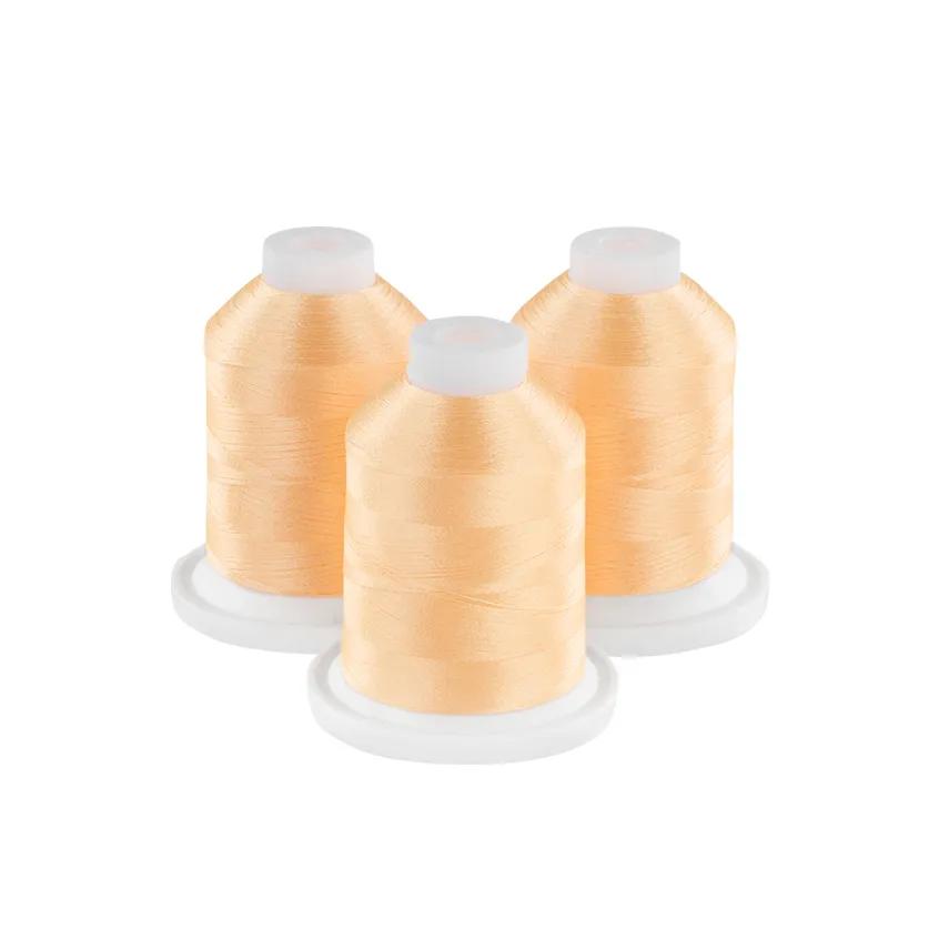 Three spools of soft melon embroidery thread on white bases