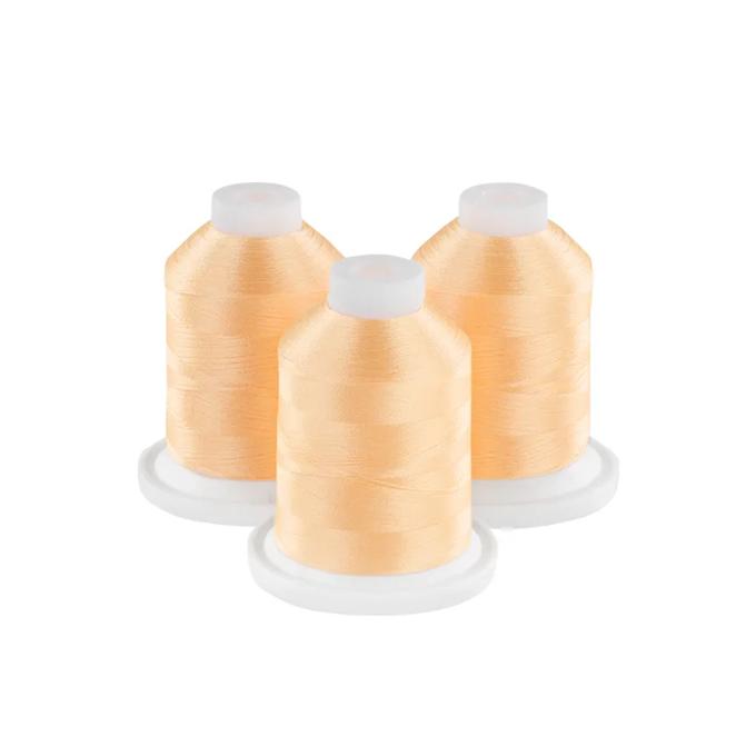 Three spools of soft melon embroidery thread on white bases