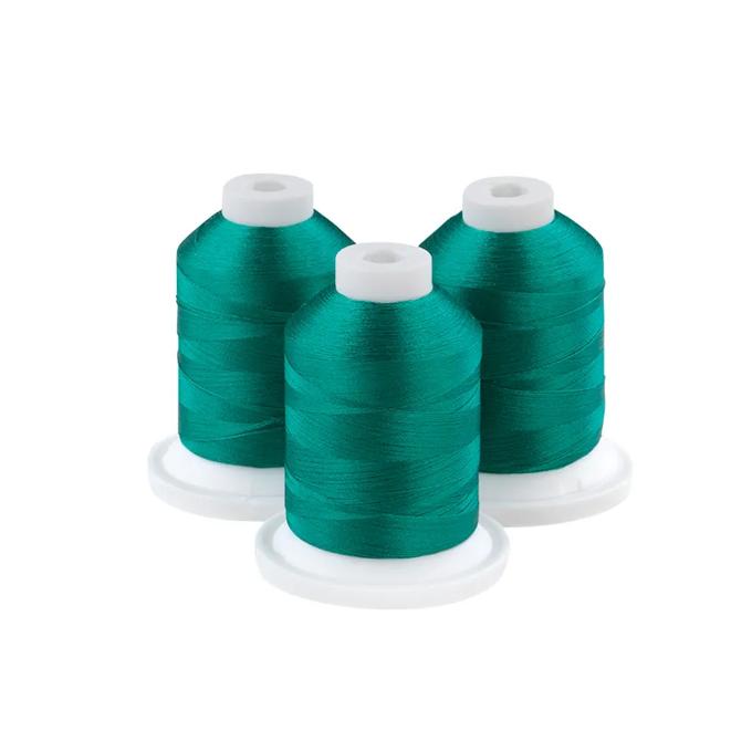 Three teal embroidery thread spools on white bases
