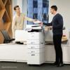 Two professionals using Brother all-in-one laser printer with multi-drawer tower in modern office