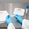Lab technician applying Brother P-touch label to sample vial in laboratory workspace