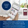 Hand holding smartphone displaying Artspira mobile app next to Brother SE725 embroidery machine