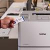 Hand inserting ID badge into Brother HL-L8570CDW color laser printer with NFC reader