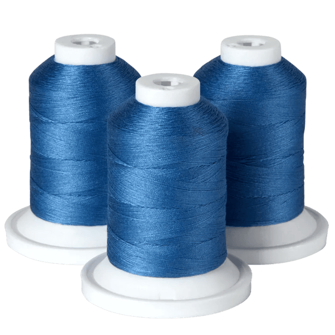 Three spools of blue embroidery thread on white bases