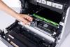 Hand replacing toner cartridge in Brother PF-M5000 monochrome printer with green drum unit visible