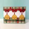 Holiday card with three gold jingle bells hanging from red bows on plaid ribbon background