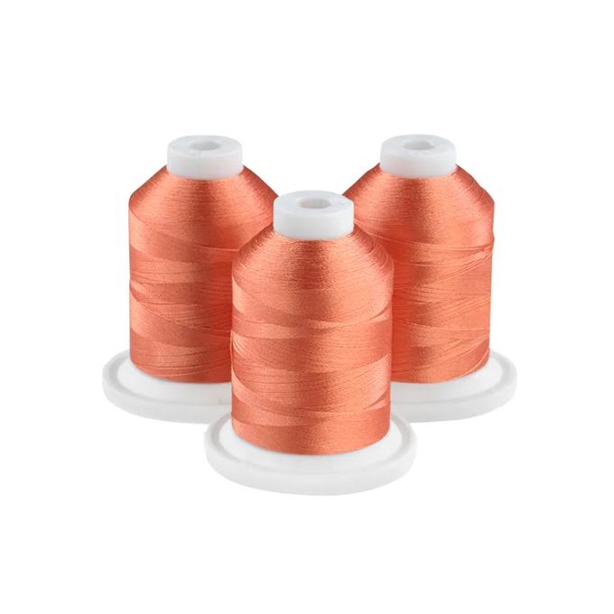 Brother embroidery thread spools in melon color with white caps on white bases