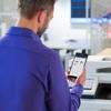 Man using smartphone to manage Brother MFC-L9610CDN wireless color laser all-in-one printer