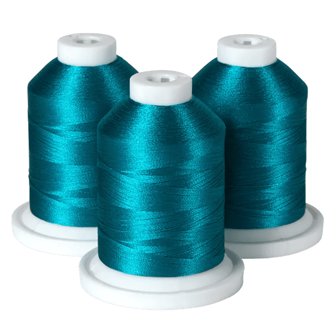 Three spools of teal embroidery thread on white bases