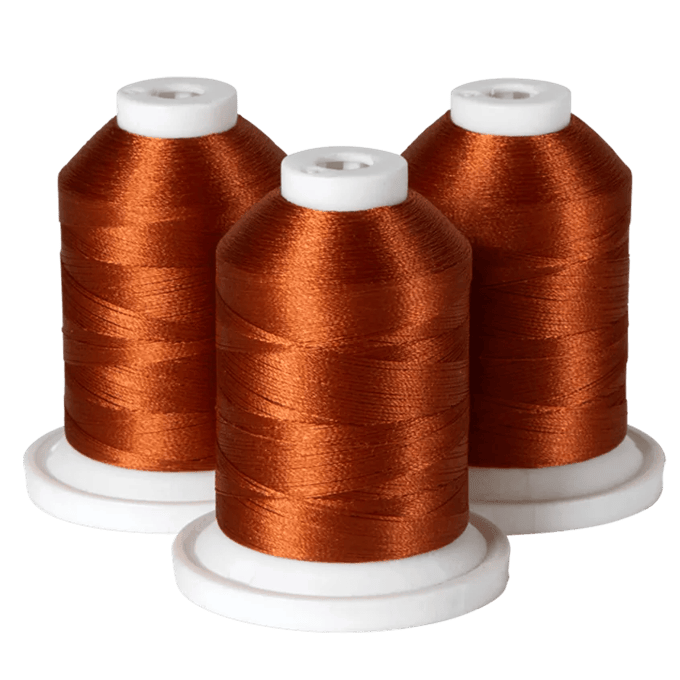 Three spools of copper-colored Brother embroidery thread on white bases