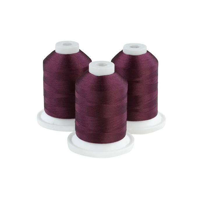 Three plum-colored embroidery thread spools on white bases