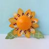Orange EOS lip balm sphere with decorative sunflower petals and green leaves on light background