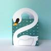 White swan-shaped card holder with teal polka dot background on light blue surface