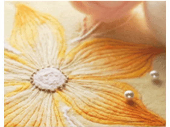 Close-up of yellow embroidered flower with metallic beads on fabric