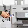 Hand inserting USB drive into Brother MFC-J6975DW all-in-one printer in office setting
