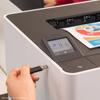 Hand inserting USB drive into Brother HL-L8430CDWT color laser printer with touchscreen