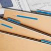 Organized wooden file folders with blue labels on a desk with fabric swatches and blueprints