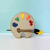Wooden artist palette with colorful paint dabs and paintbrush on white surface